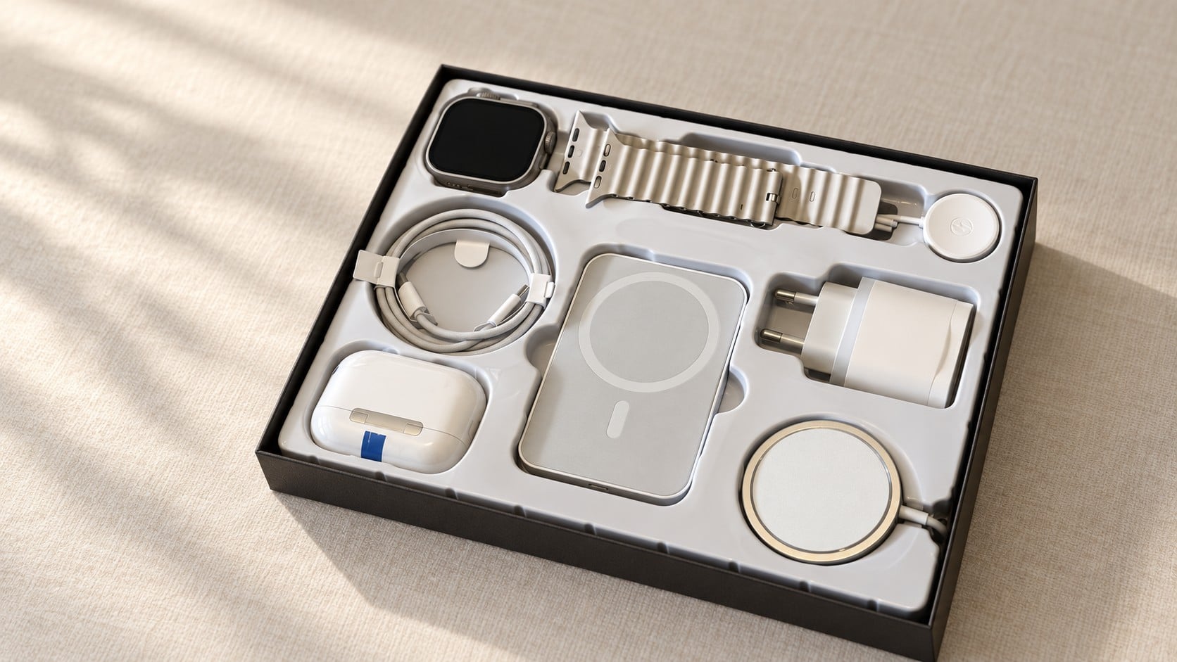 Le Coffret Tech ouvert : montre, bracelet, écouteurs, batterie et chargeurs rangés dans le coffret